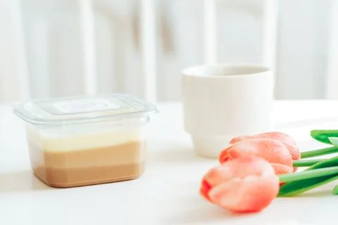 Three types of chocolate in plastic container next to coffee and tulips Stock Photos