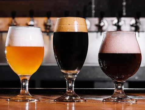 Three types of craft beer in glasses on table in pub interior Stock Photos