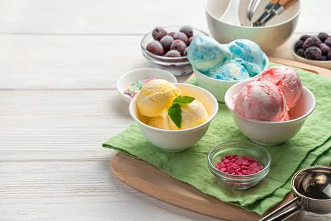 Three types of ice cream in white cups on a light background. Stock Photos
