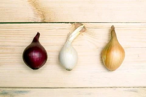 Three types of onions red white and yellow on a wooden table Stock Photos