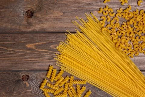 Three types of wheat pasta on the background of a brown wooden table.the loca Stock Photos
