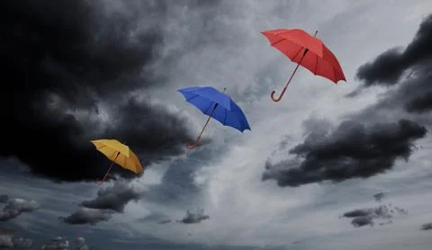 Three umbrellas floating through cloudy sky Foto stock
