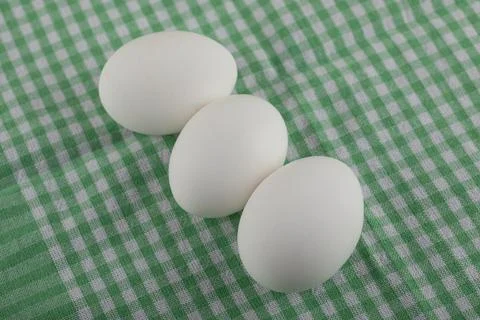 Three uncooked eggs on striped tablecloth Stock Photos