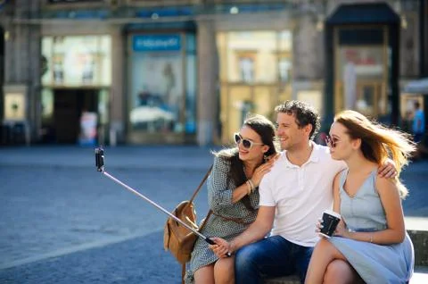 Three undergraduate makes selfie on the background of an old building. Stock Photos
