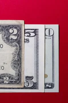 Three US dollar bills layered to form number 250 on a red background. Financi Stock Photos