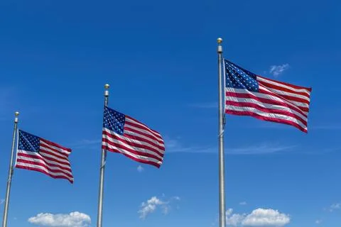 Three US flags and bright blue sky. Stock Photos