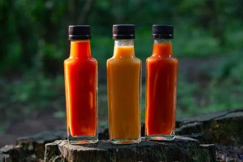 Three Varieties Of Hot Sauce On A Tree Stump 스톡 사진