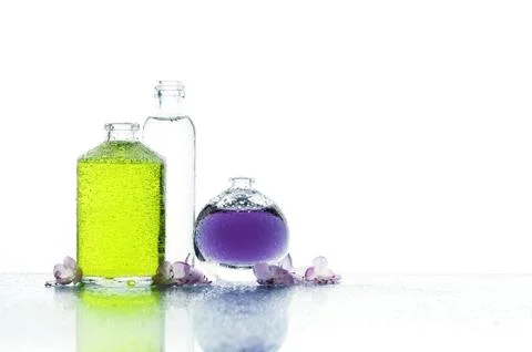 Three various bottles with color liquid and flowers Stock Photos