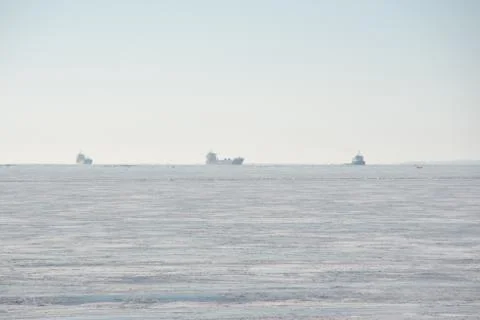 Three vessels on the horizon in frozen sea Stock Photos
