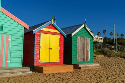 Three Vibrantly Painted Bathing Boxes Stand on a Sandy Beach Under a Clear .. Stock Photos