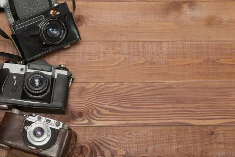 Three vintage camera in their cases on the wooden background Stock Photos