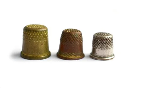Three vintage thimbles stand in a row isolated on a white background. Stock Illustration