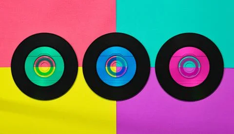 Three vinyl CD discs in flat lay format displayed on a colorful background. Stock Photos