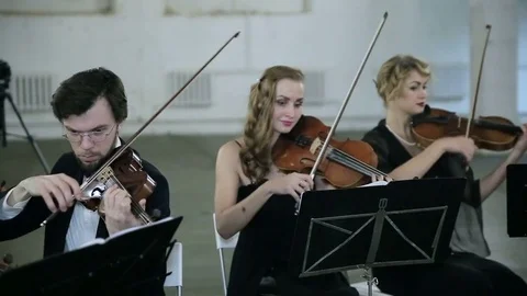 Three violinists and conductor playing music Stock Footage 73587722