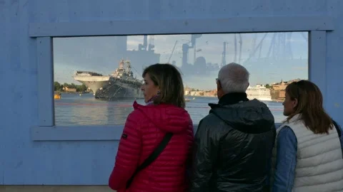 Three visitors watch a US Navy warship across Stockholm waterfront Stock Footage 320744272