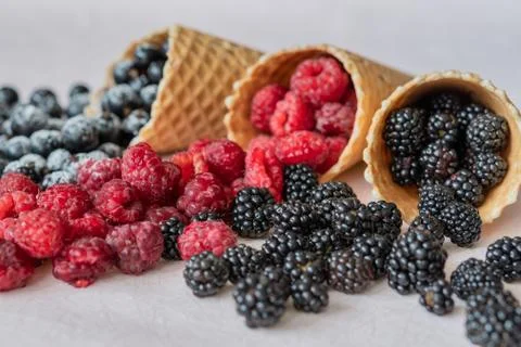 Three waffle cones close-up of which poured on the table raspberries, currants Stock Photos