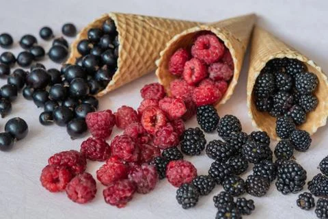 Three waffle cones close-up of which poured on the table raspberries, currants Foto stock