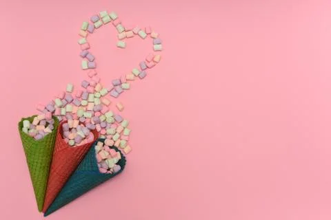 Three waffles cones and marshmallows heart on a pink background Foto stock