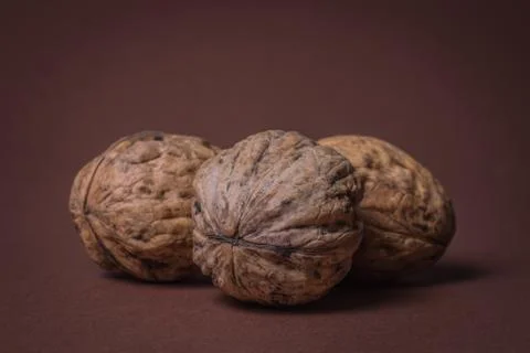 Three Walnut walnuts on a dark brown background Stock Photos