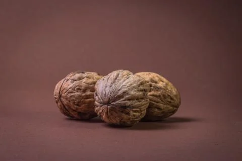 Three Walnut walnuts on a dark brown background Stock Photos