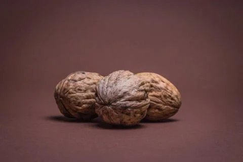 Three Walnut walnuts on a dark brown background Stock Photos