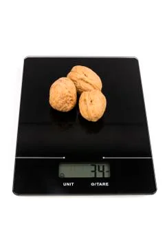 Three walnuts in the shell on a digital scale isolated over white Stock Photos