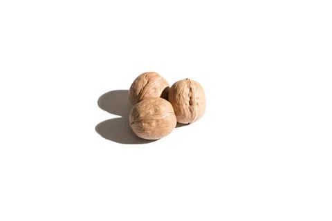 Three walnuts on a white background. Hard shadows. Isolated Stock Photos