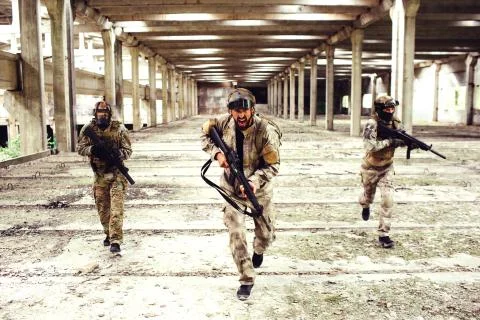 Three warriors with equipment is running down big and bright room. Two of them Foto stock