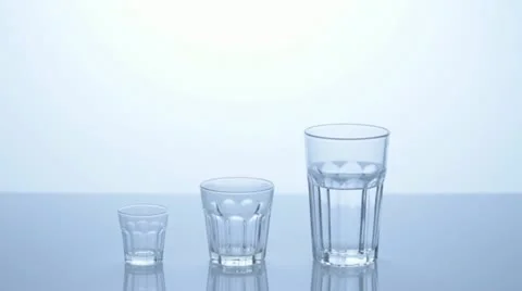 Three water glasses - pouring into another - overflowing. Stock Footage 11606369