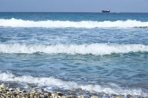 Three waves near the shore. a blurred ship on the horizon Stock Photos