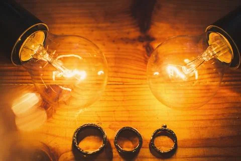 Three wedding rings and two light bulbs on the table Stock Photos