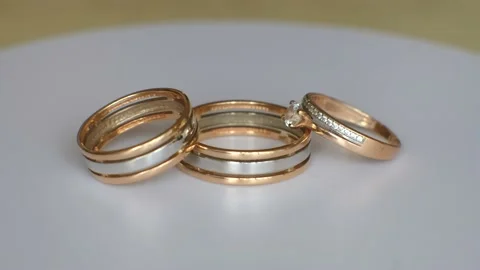 Three wedding rings made of gold and platinum rotate on a white table. Stock Footage 165794038