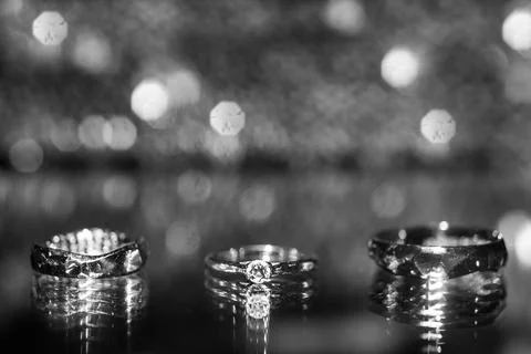 Three wedding rings on the reflecting surface with highlights Stock Photos