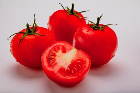 Three wet tomatoes plus one cut Stock Photos