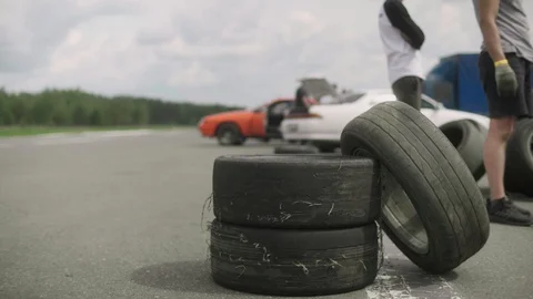 Three wheels stacked on top of each other at the edge of the road. Car drives by Video stock 129345815