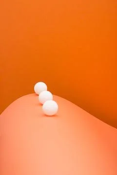 Three white balls on an abstract background made of colored sheets of paper Stock Photos
