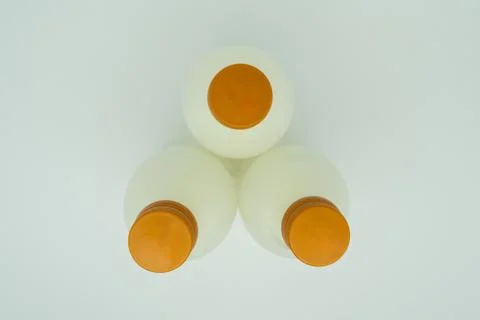 Three white bottles with orange caps on white background Stock Photos