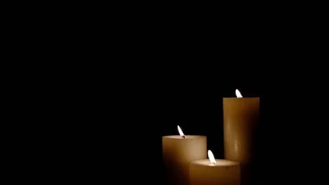 Three white burning candles blowing out. Isolated candles burning over dark b Stock Footage 149569980