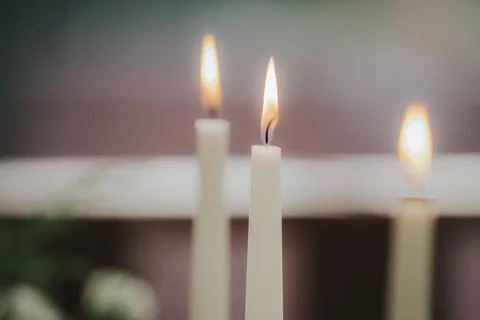 Three white candles with flames burning brightly, arranged in a decorative .. Stock Photos