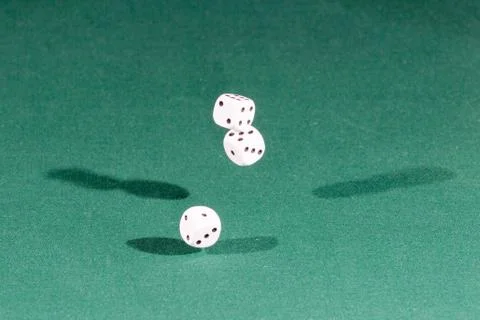 Three white dices falling on a green table Foto stock