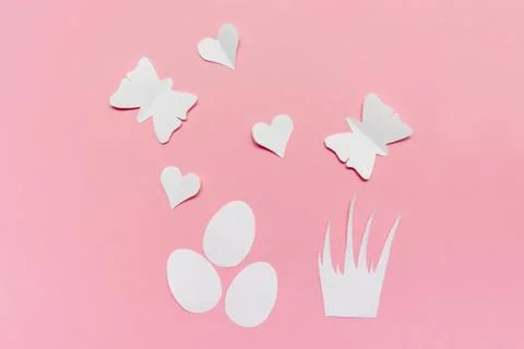 Three white easter eggs, grass, hearts and butterflies cut of paper on pink b Stock Photos
