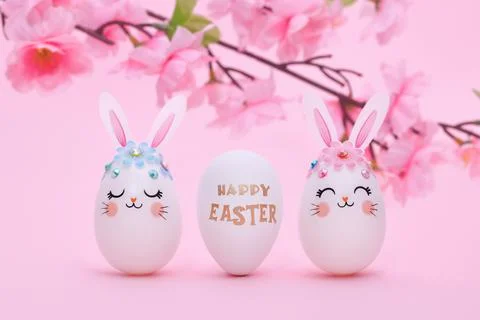 Three white Easter eggs a pink background with a flowering branch of an apple Stock Photos
