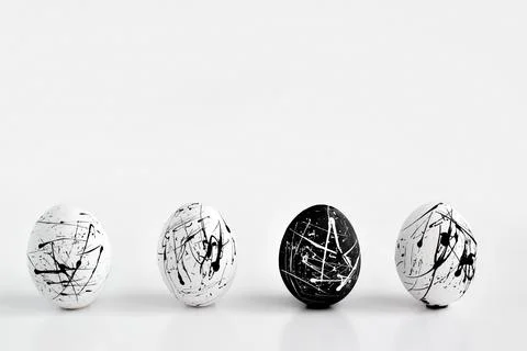 Three white eggs and one black speckled egg. Easter. Minimalism. The concept Stock Photos
