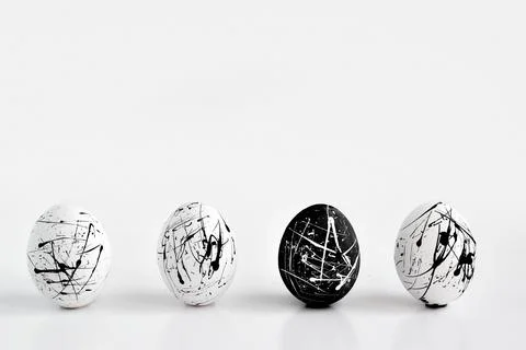 Three white eggs and one black speckled egg. Easter. Minimalism. The concept Stock Photos