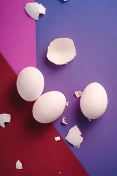 Three white eggs with eggshell pieces on red, pink and blue colors Stock Photos