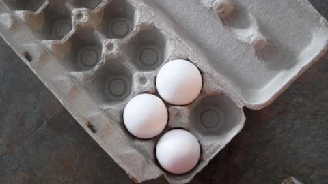 Three white fresh eggs in a crate Stock Photos