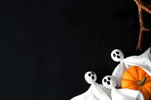 Three white ghosts hold orange pumpkin on black background, halloween symbols Stock Photos