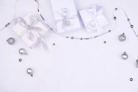 Three white gift boxes and silver baubles. Stock Photos