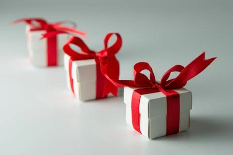 Three white gift boxes with red ribbon in a row Stock Photos