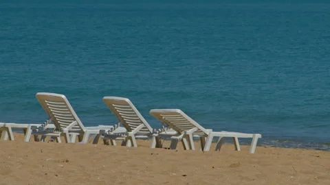 Three White Lounge Chairs on a Sandy Beach Stock Footage 312291484